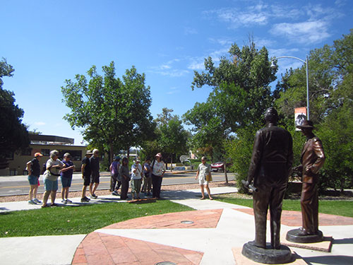 Teachers listening to the guide explain the context of the statue of J. Robert Oppenheimer and Gen. Leslie Groves