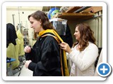Academic Programs Coordinator Alisa Gibson adjusts Lecturer III Leandra Boucheron's hood and gown