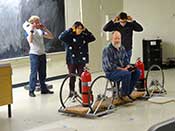 Students protect their ears before demonstrating the rocket car. Professor Paul Schwoebel is the rocket car passenger